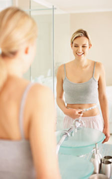 Woman Measuring Waist in Mirror